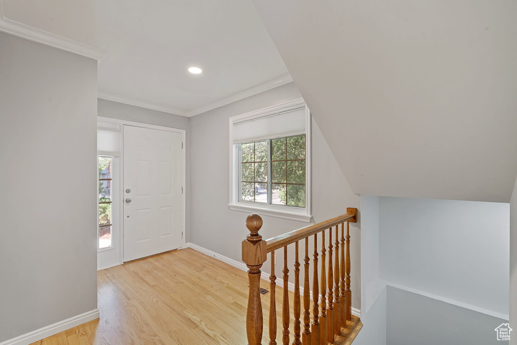 Entrance foyer with ornamental molding, a wealth of natural light, and light hardwood / wood-style floors