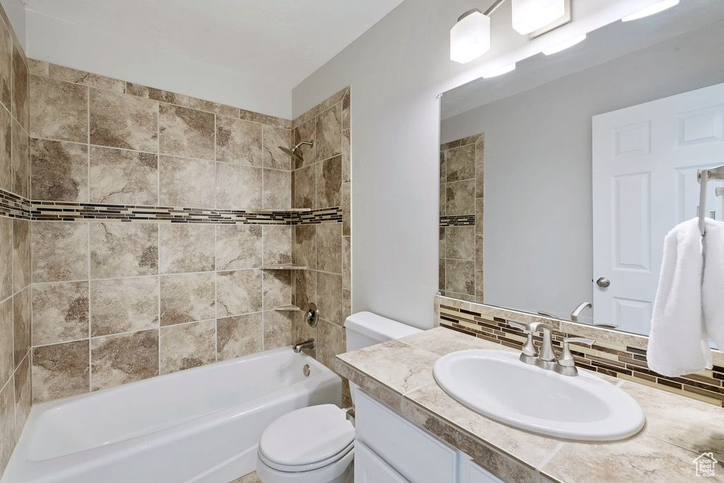 Full bathroom featuring tiled shower / bath, toilet, vanity, and backsplash