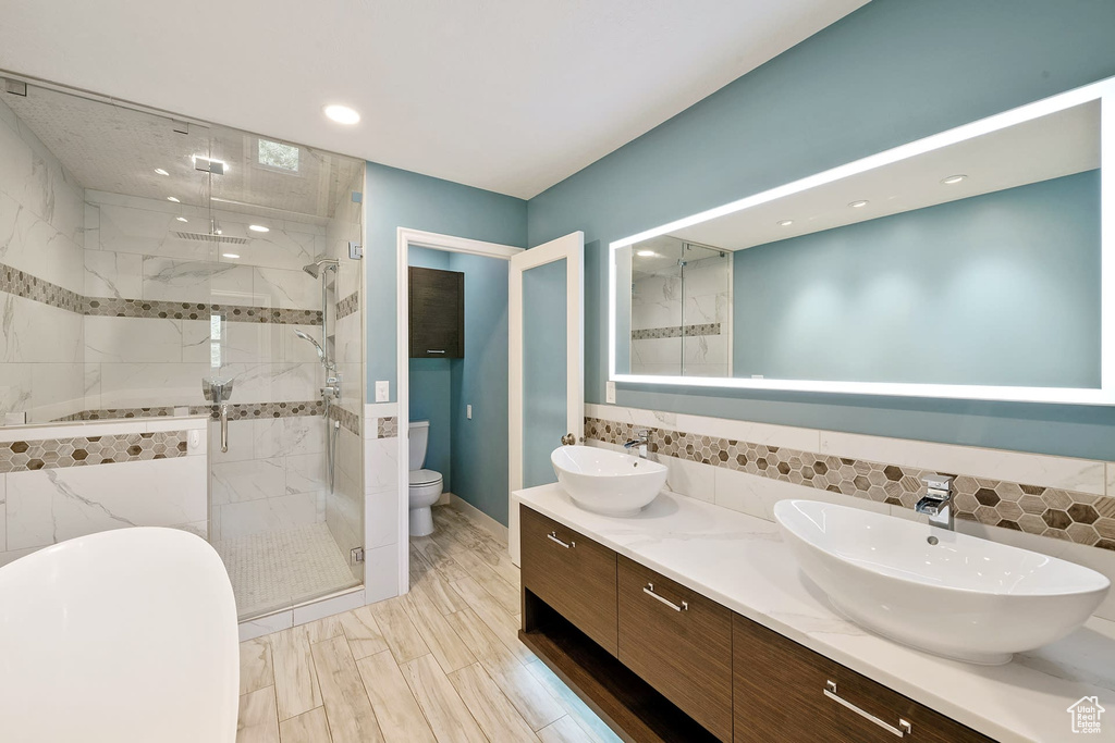 Bathroom featuring toilet, dual vanity, walk in shower, and tile walls