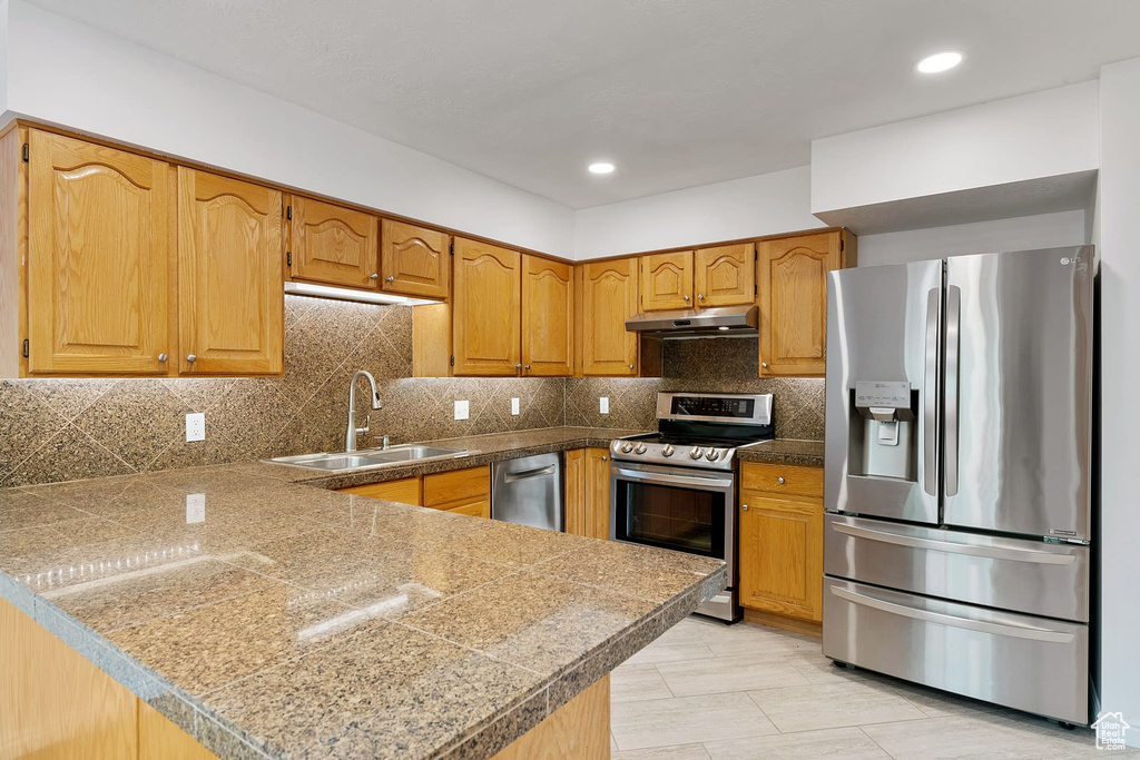 Kitchen featuring tasteful backsplash, stainless steel appliances, sink, and kitchen peninsula