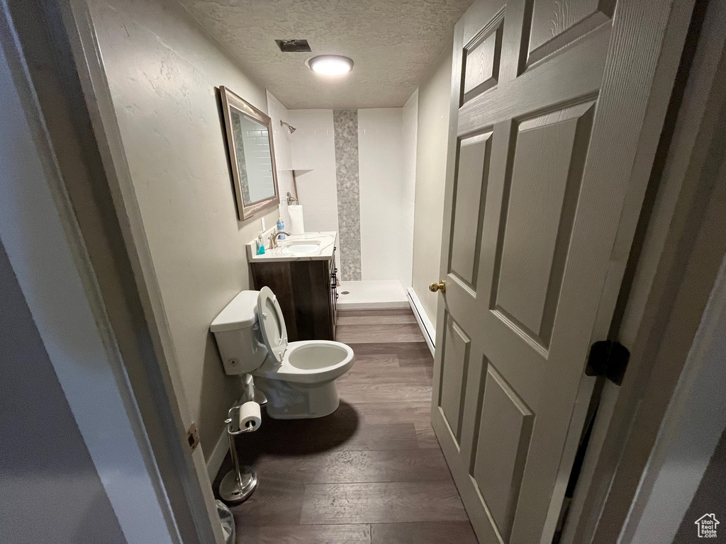 Bathroom featuring toilet, hardwood / wood-style flooring, vanity, and a textured ceiling