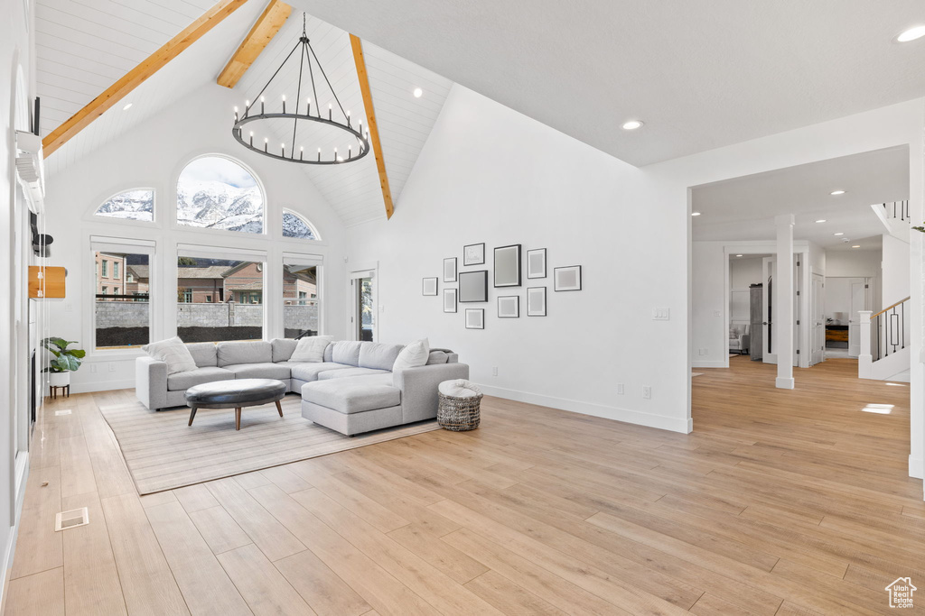 Living room with light hardwood / wood-style floors, beamed ceiling, high vaulted ceiling, and a chandelier