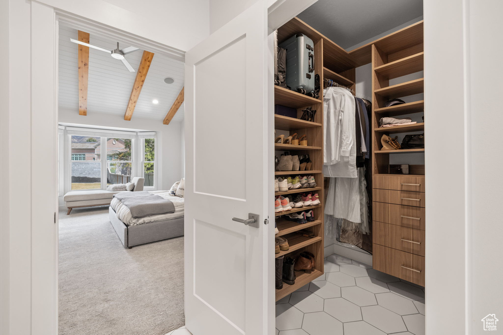 Spacious closet featuring ceiling fan, lofted ceiling with beams, and light tile floors