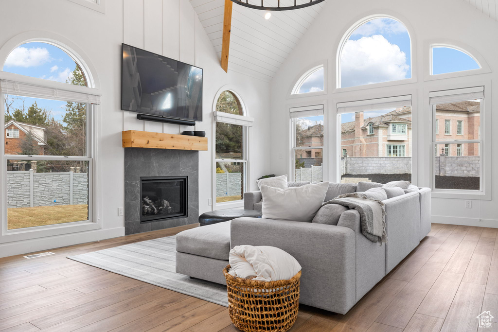 Living room with plenty of natural light, high vaulted ceiling, and light hardwood / wood-style floors