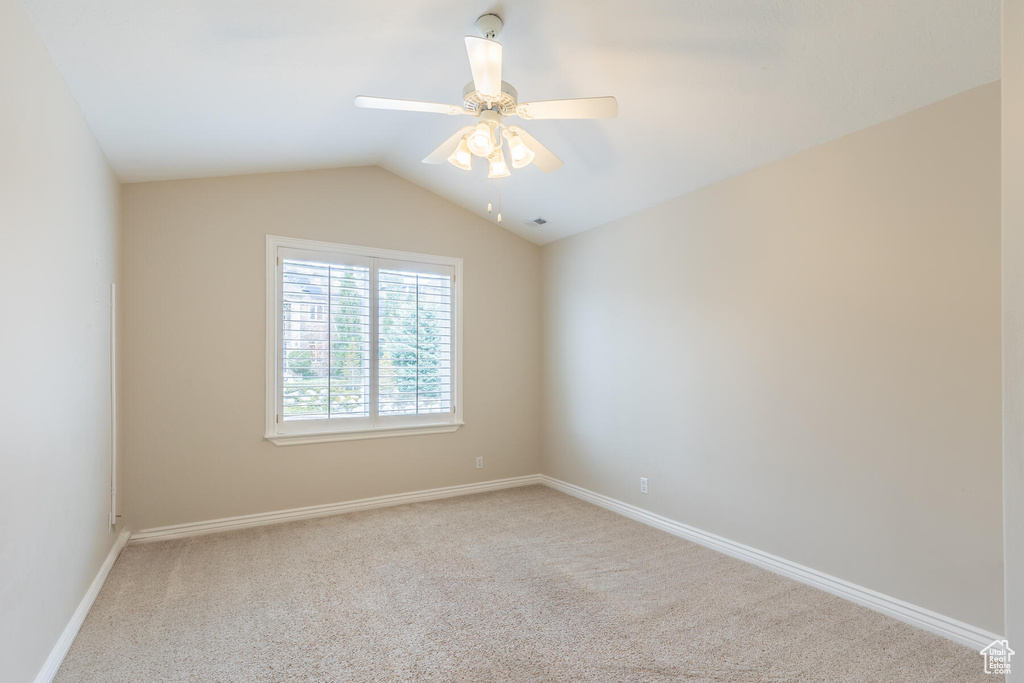 Empty room with lofted ceiling, ceiling fan, and light colored carpet