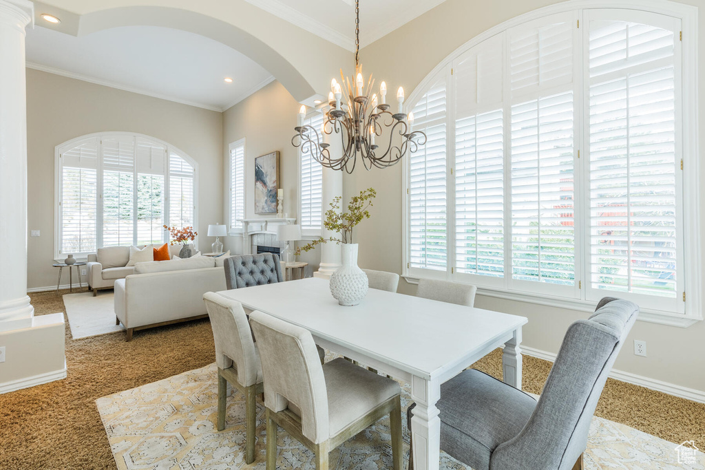 Dining area featuring an inviting chandelier, plenty of natural light, and light colored carpet