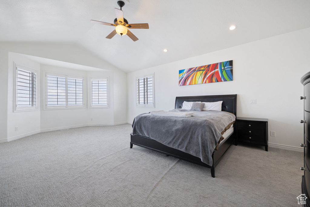 Bedroom with light carpet, multiple windows, ceiling fan, and vaulted ceiling