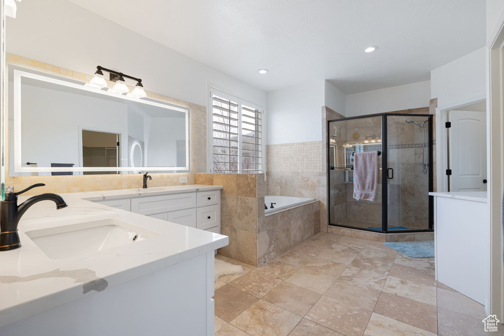 Bathroom featuring tile floors, independent shower and bath, and dual bowl vanity