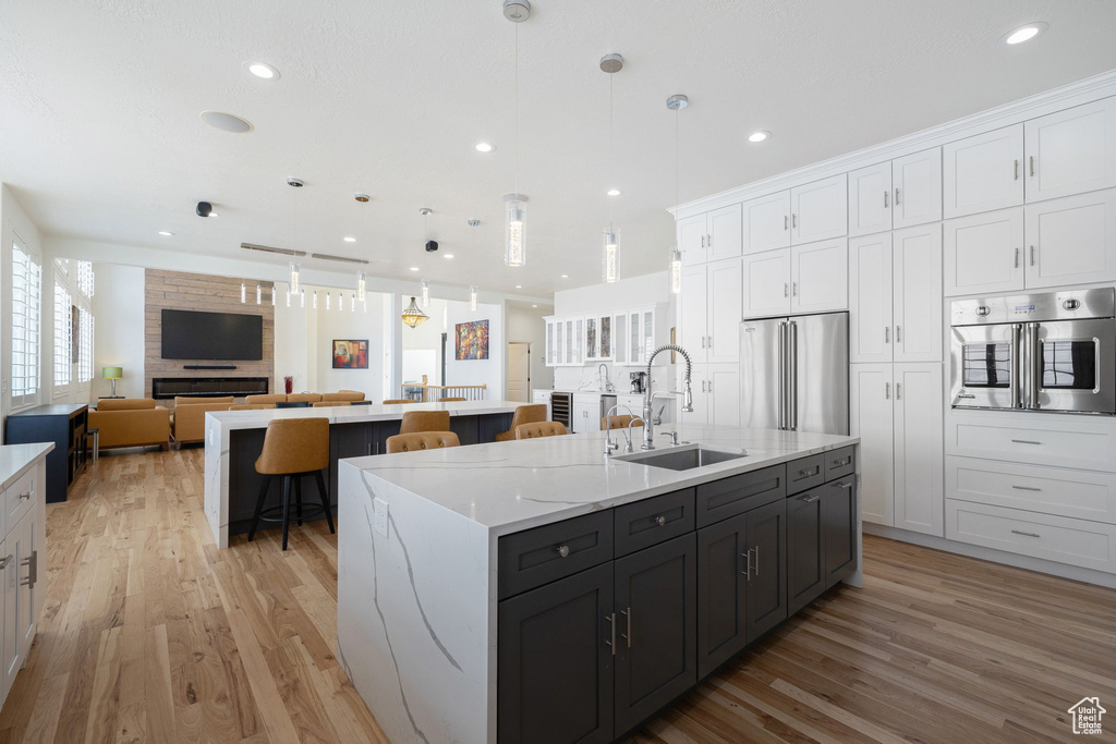 Kitchen featuring light hardwood / wood-style floors, a center island with sink, stainless steel appliances, and sink