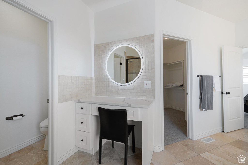 Bathroom featuring toilet, tile floors, tasteful backsplash, and vanity