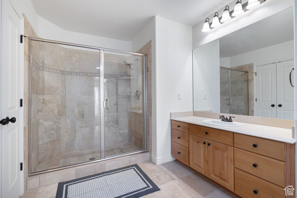 Bathroom with tile flooring, an enclosed shower, vanity, and a textured ceiling