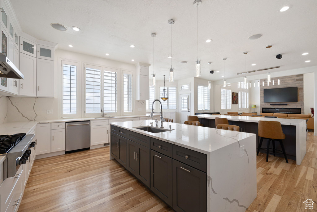 Kitchen featuring an island with sink, decorative light fixtures, and sink
