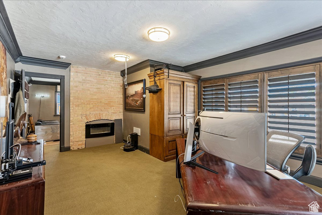 Office area featuring brick wall, a brick fireplace, ornamental molding, carpet flooring, and a textured ceiling