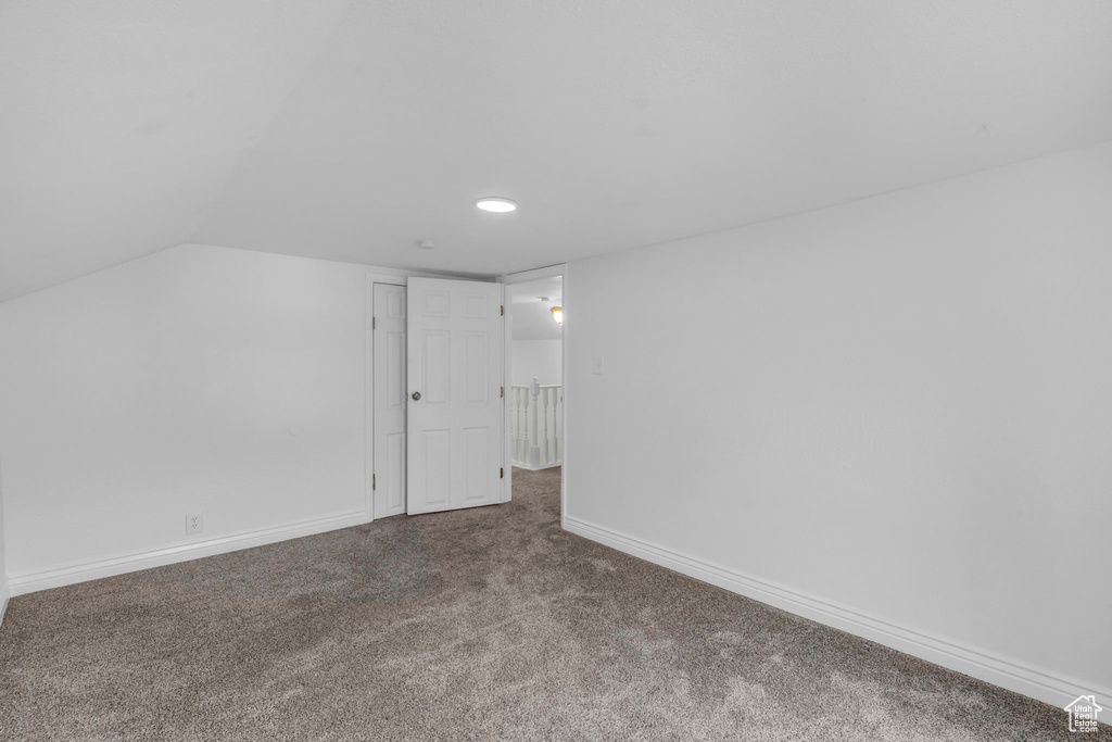 Carpeted empty room with vaulted ceiling