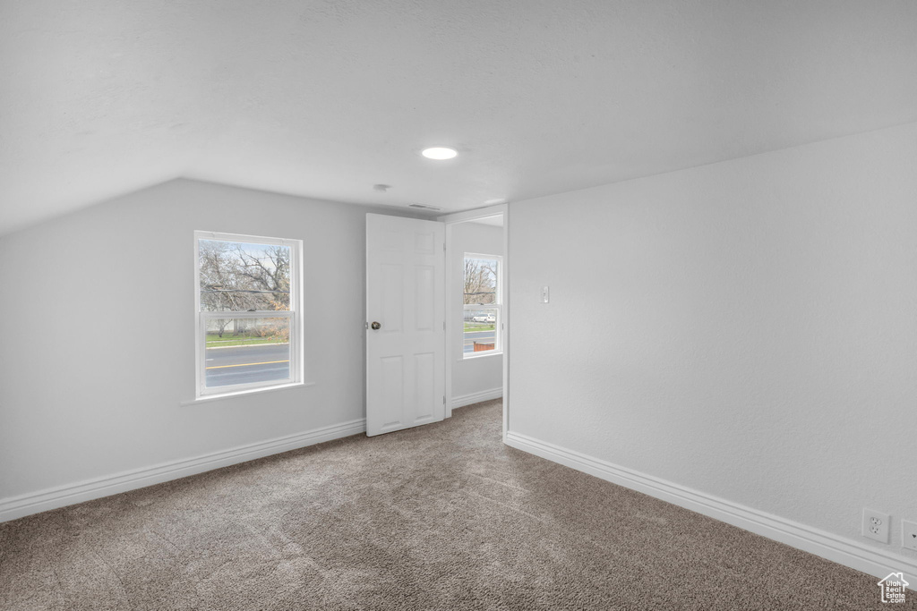 Empty room featuring lofted ceiling and light colored carpet