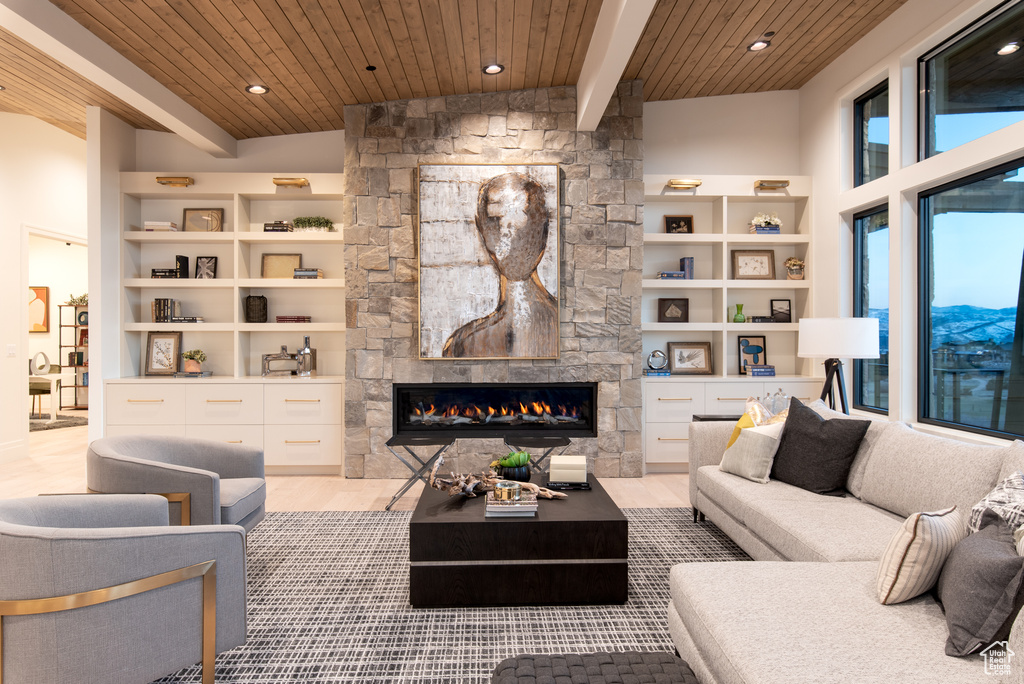 Living room with built in features, vaulted ceiling with beams, wooden ceiling, a fireplace, and a mountain view