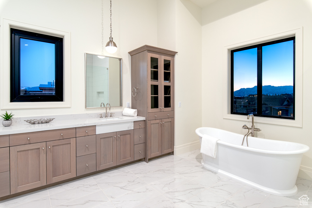 Bathroom featuring tile flooring, a mountain view, dual bowl vanity, and a bath to relax in