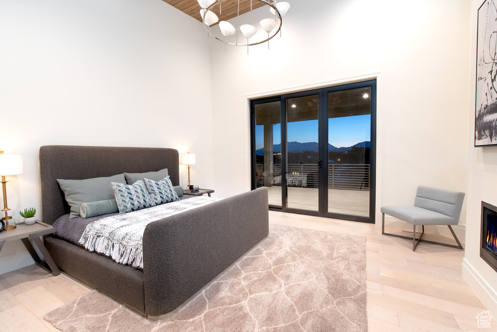 Bedroom featuring a mountain view, light hardwood / wood-style floors, a high ceiling, access to outside, and an inviting chandelier