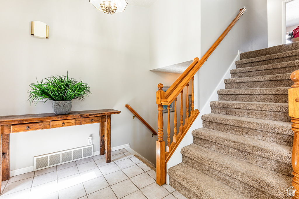 Staircase featuring light tile flooring and an inviting chandelier