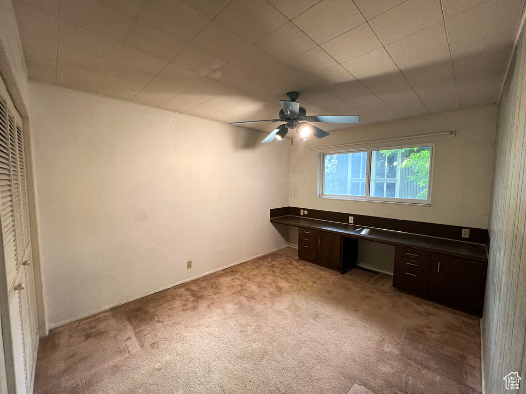 Unfurnished office featuring ceiling fan and light carpet