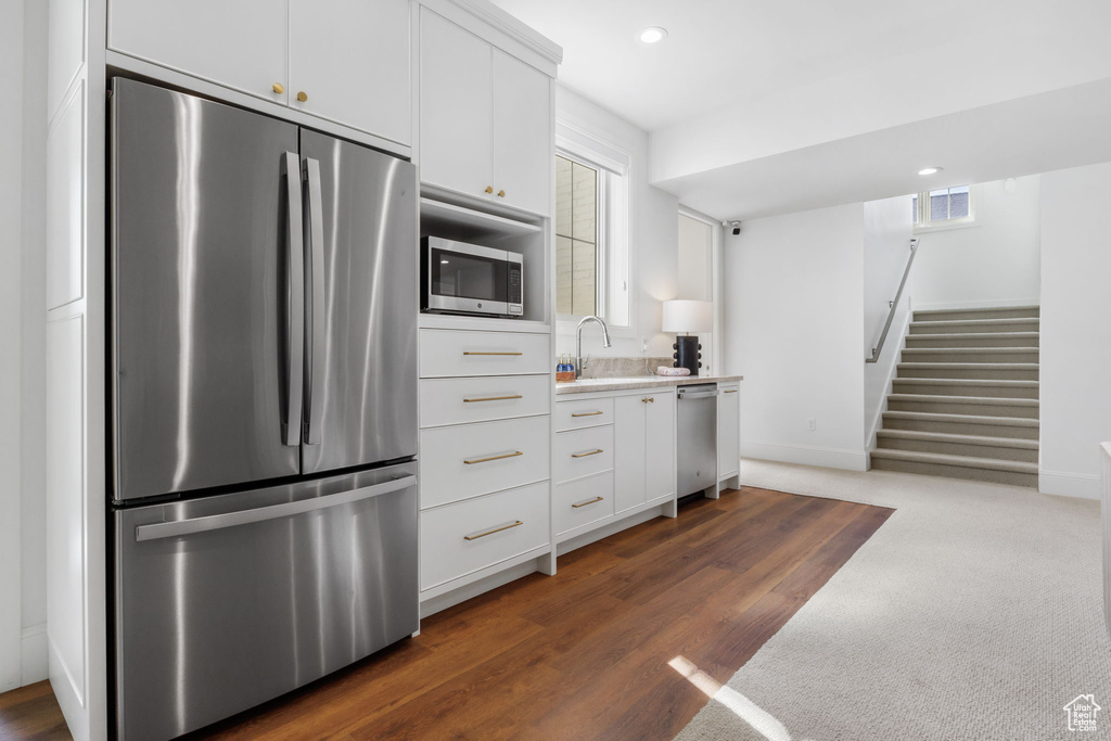 Kitchen featuring sink, stainless steel appliances, dark carpet, and white cabinets
