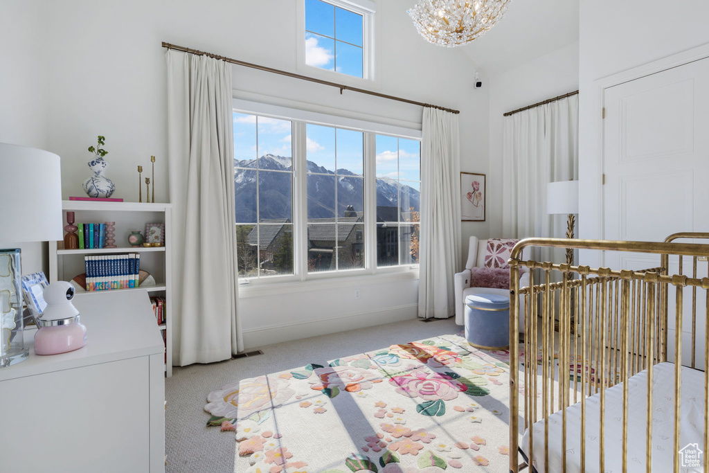 Bedroom with light carpet, a notable chandelier, a crib, a mountain view, and lofted ceiling