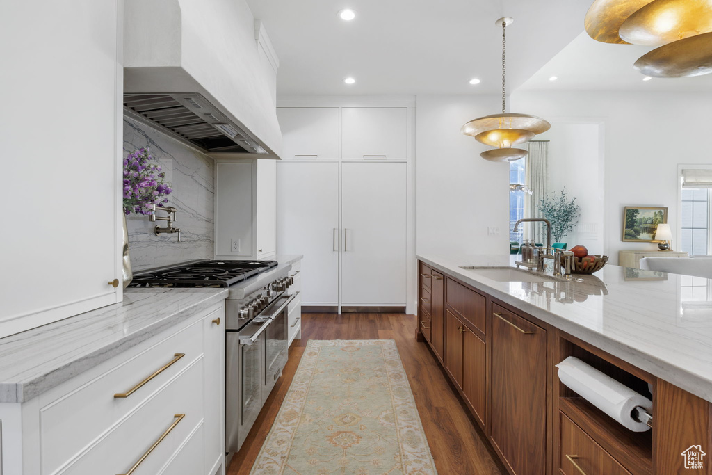 Kitchen featuring dark hardwood / wood-style flooring, backsplash, white cabinetry, range with two ovens, and premium range hood