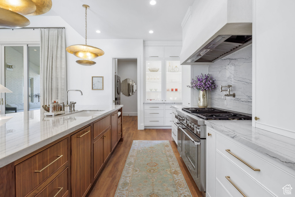 Kitchen featuring decorative light fixtures, white cabinetry, custom range hood, double oven range, and backsplash