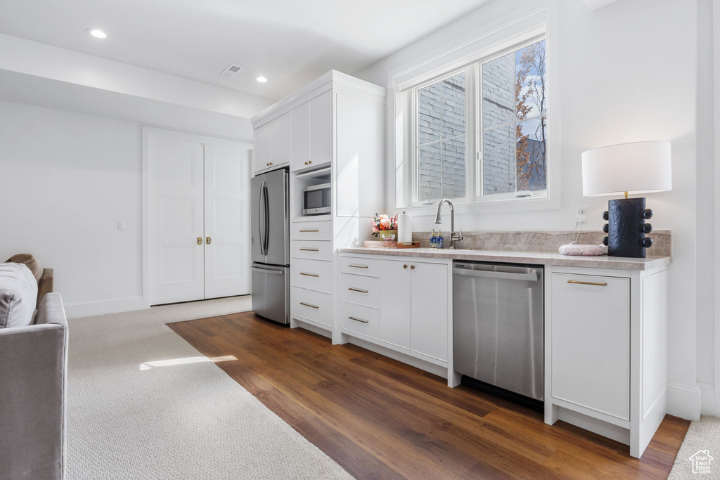 Kitchen with stainless steel appliances, dark wood-type flooring, and white cabinetry