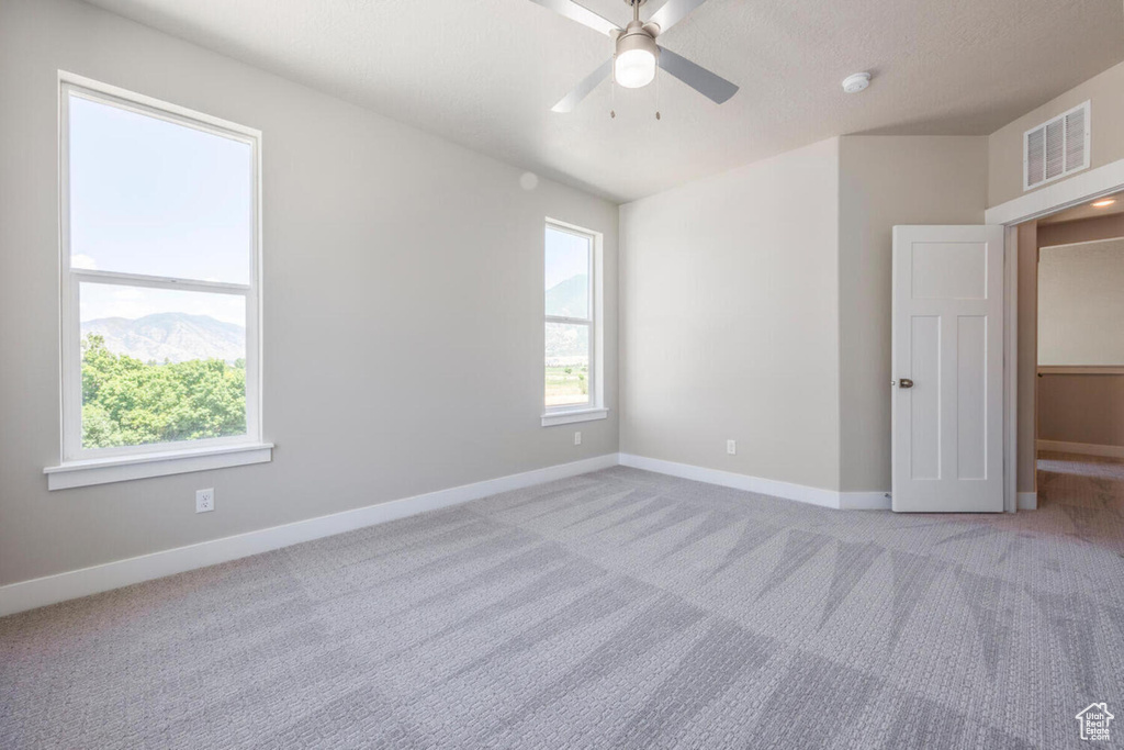 Spare room featuring light colored carpet and ceiling fan