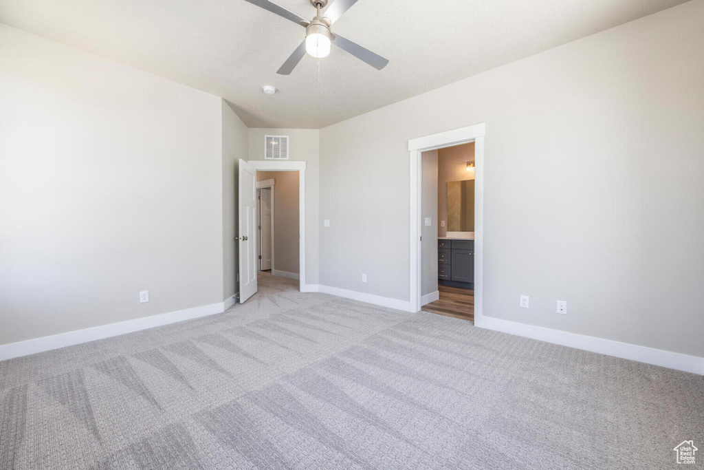 Unfurnished bedroom with ceiling fan, connected bathroom, and light colored carpet