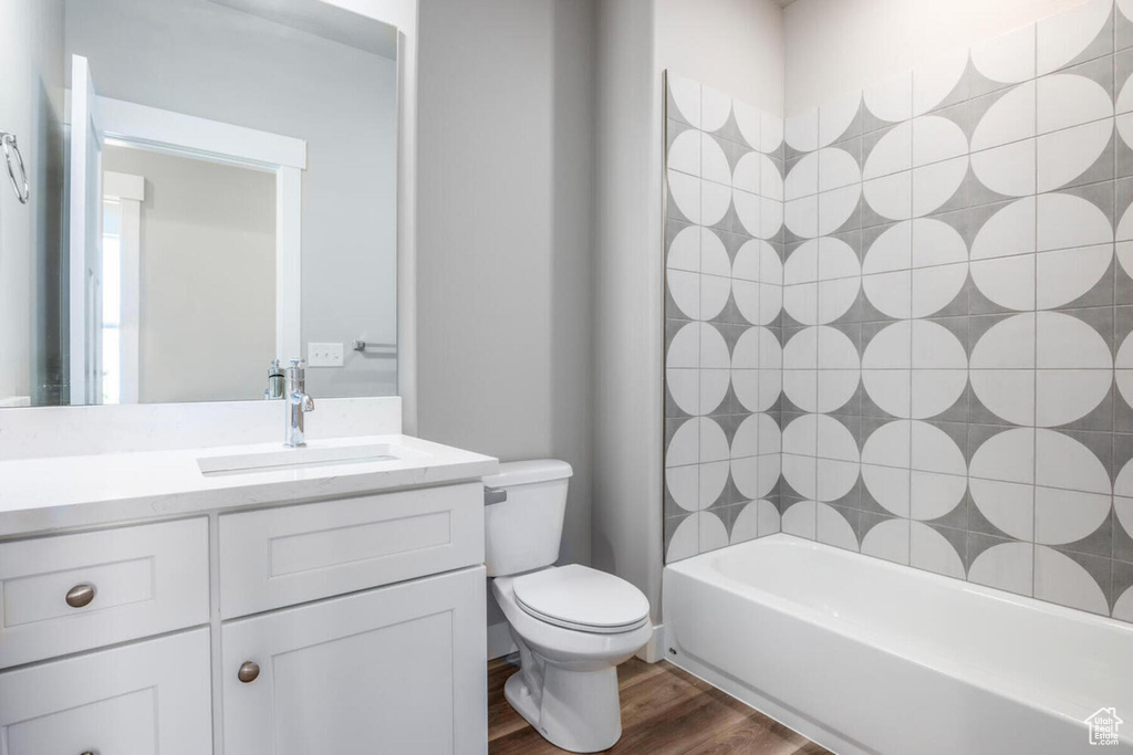 Full bathroom featuring tiled shower / bath, vanity, toilet, and hardwood / wood-style floors