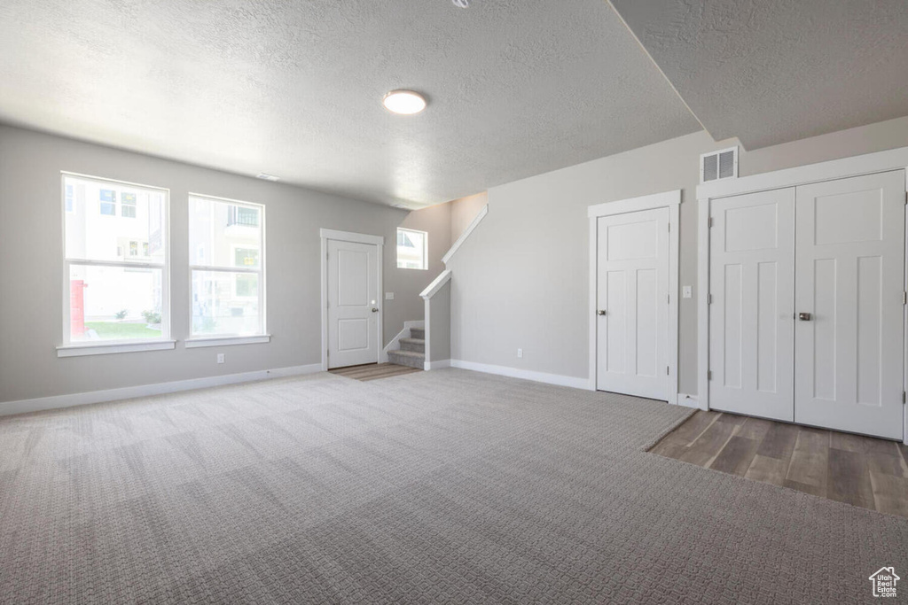 Empty room with a textured ceiling and dark carpet