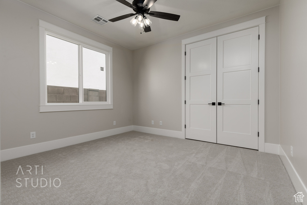 Unfurnished bedroom featuring light colored carpet, ceiling fan, and a closet