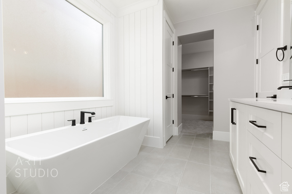 Bathroom featuring a bath, vanity, and tile floors