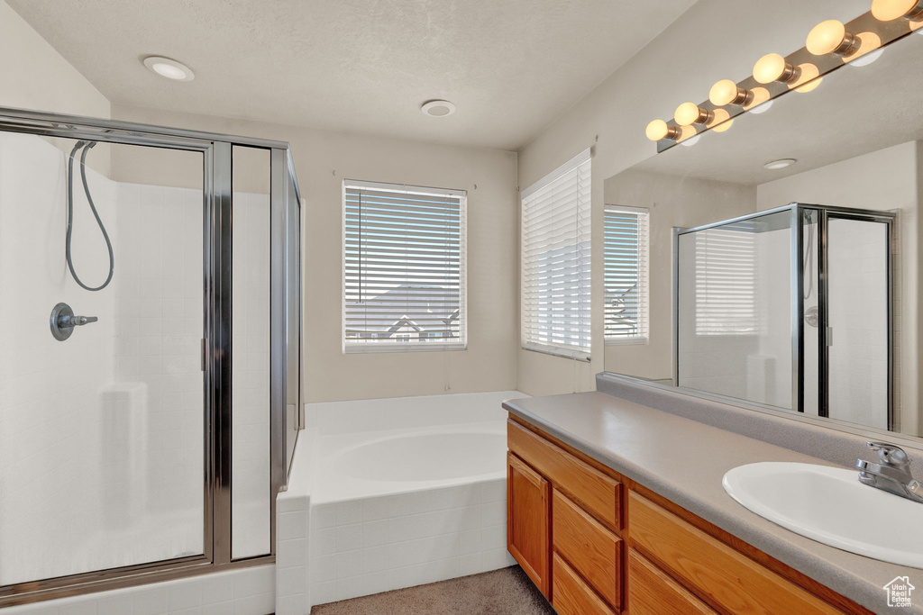 Bathroom featuring shower with separate bathtub, large vanity, and a textured ceiling