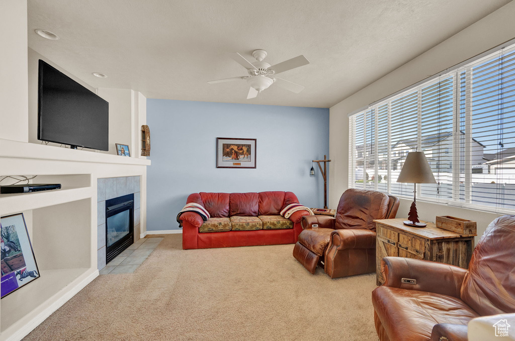 Living room with built in shelves, light colored carpet, ceiling fan, and a tiled fireplace
