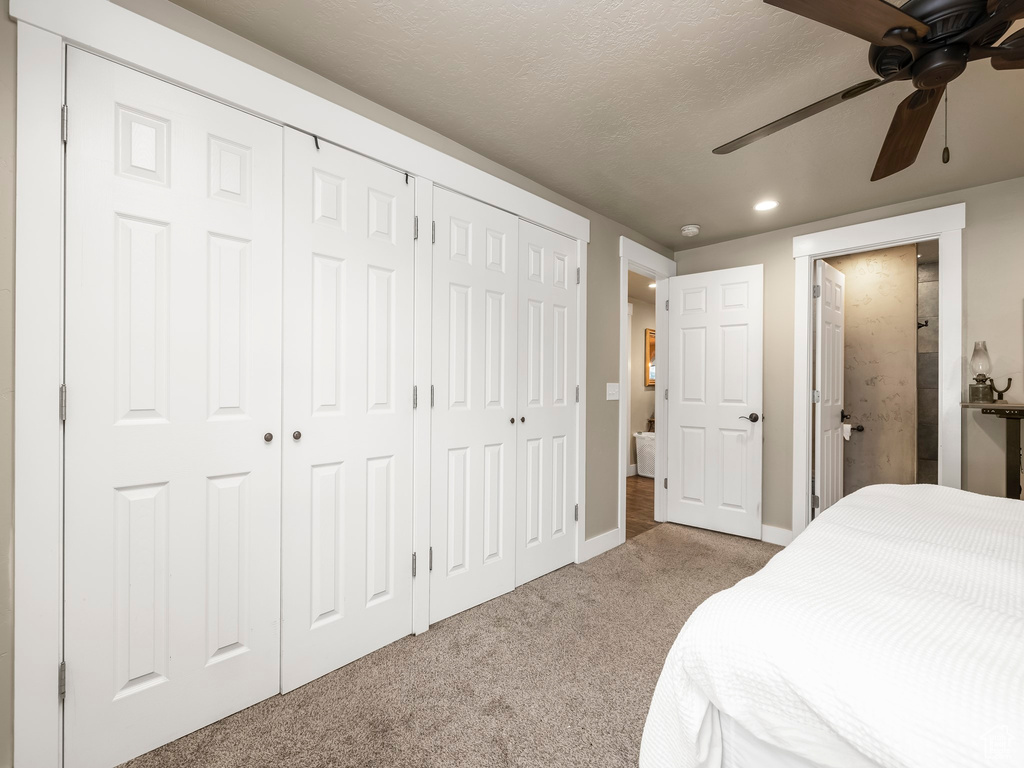 Carpeted bedroom featuring multiple closets, ceiling fan, and a textured ceiling