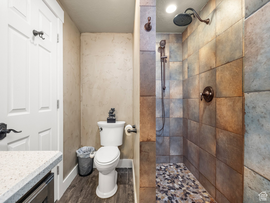 Bathroom featuring vanity, tiled shower, a textured ceiling, toilet, and hardwood / wood-style flooring