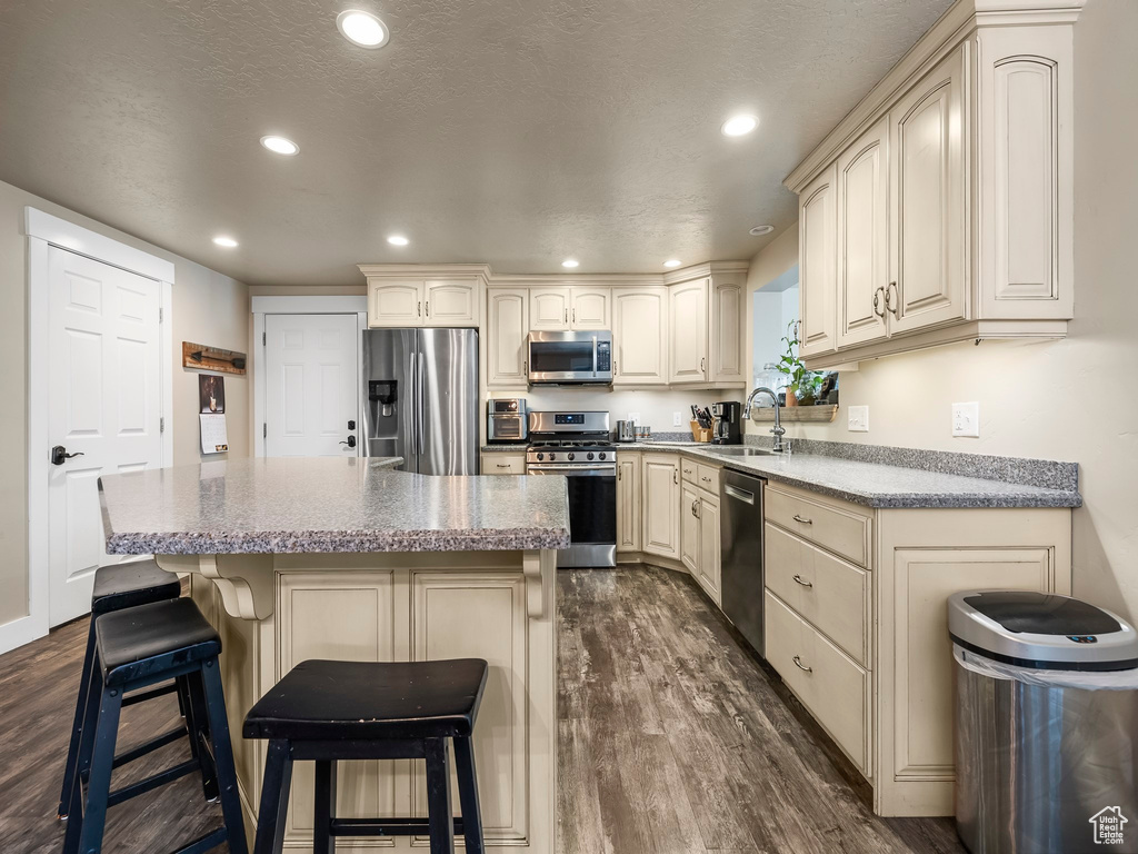 Kitchen featuring appliances with stainless steel finishes, dark hardwood / wood-style floors, a breakfast bar, and a center island