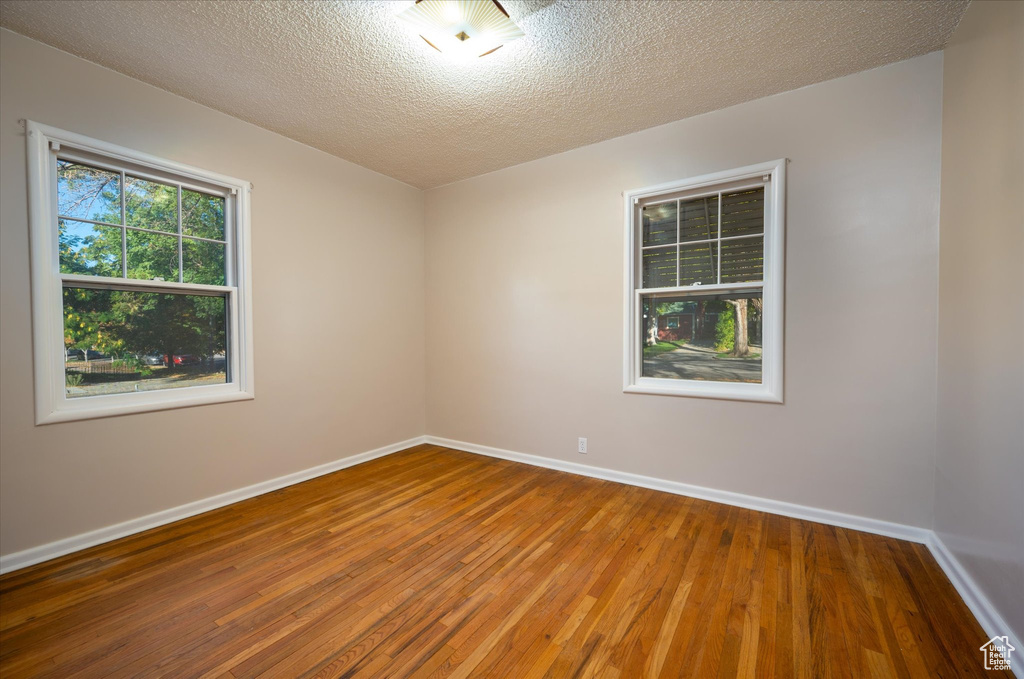 Unfurnished room with hardwood / wood-style floors and a textured ceiling