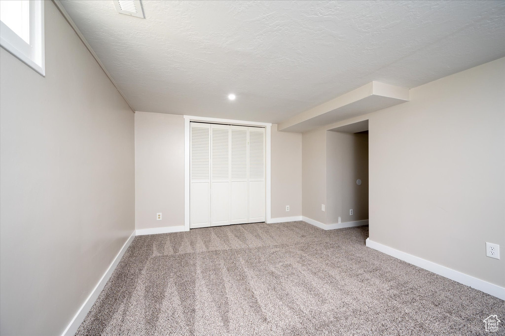 Unfurnished bedroom with a textured ceiling, light carpet, and a closet
