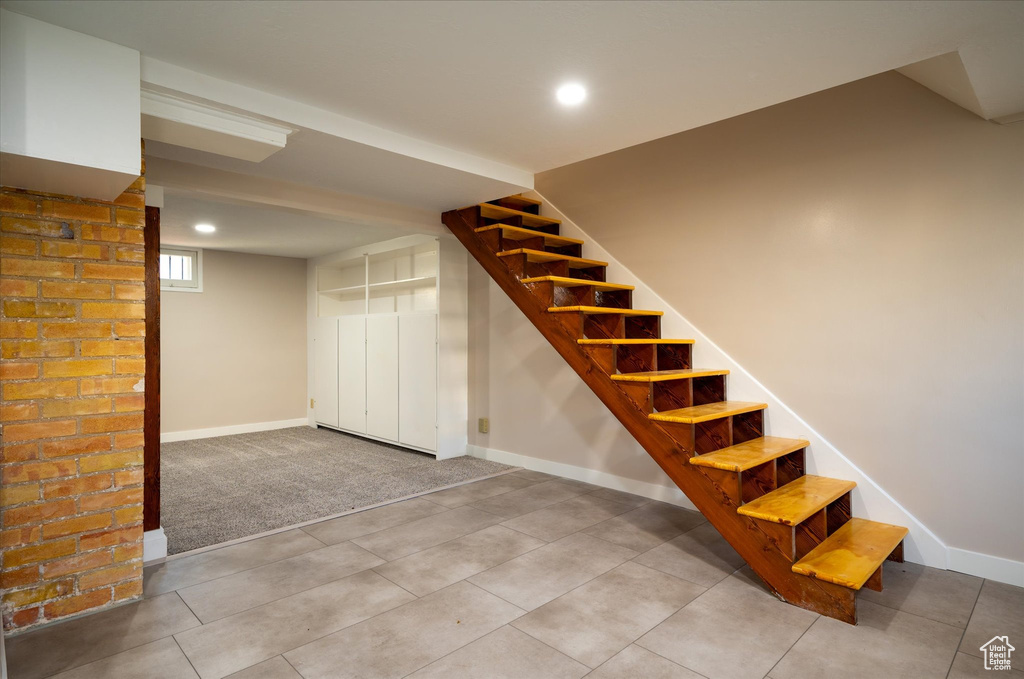 Stairs with brick wall and light tile floors