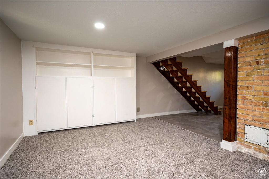 Basement with brick wall and dark colored carpet