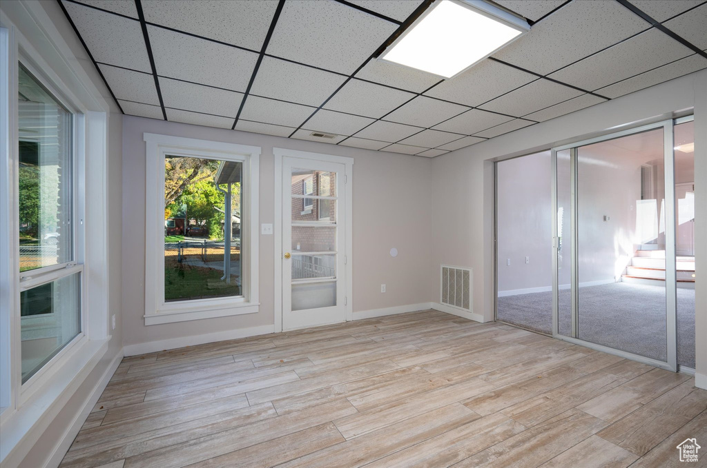 Unfurnished room featuring light hardwood / wood-style floors and a drop ceiling