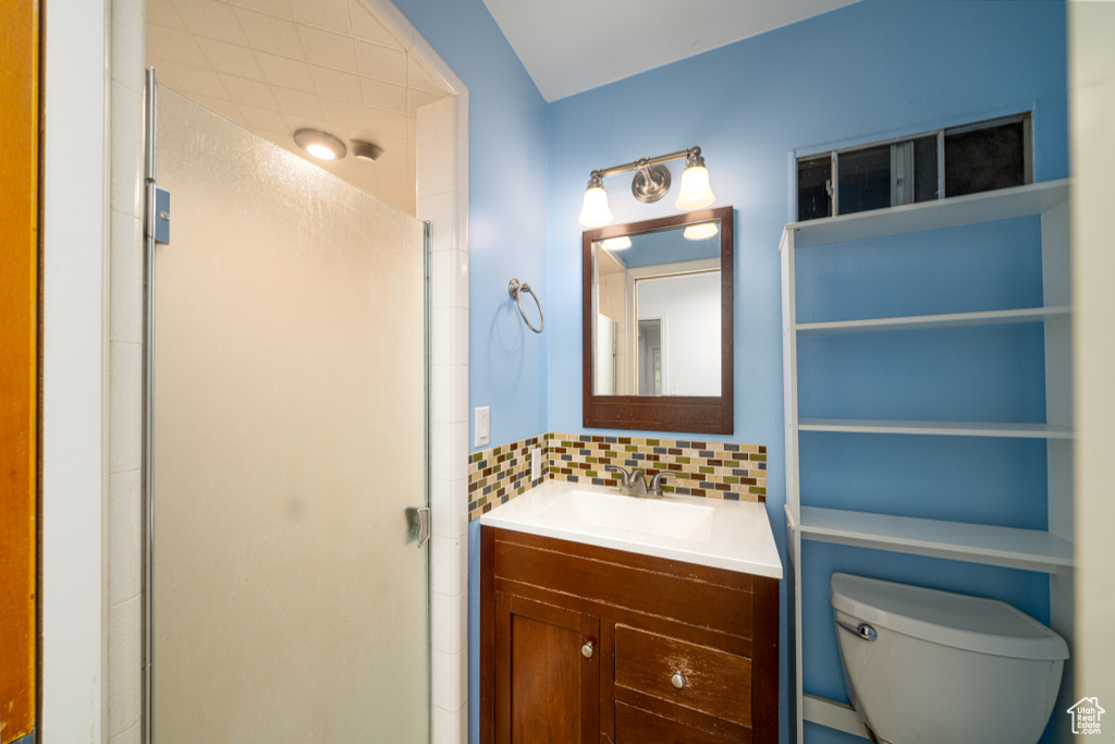 Bathroom with walk in shower, backsplash, toilet, and vanity with extensive cabinet space