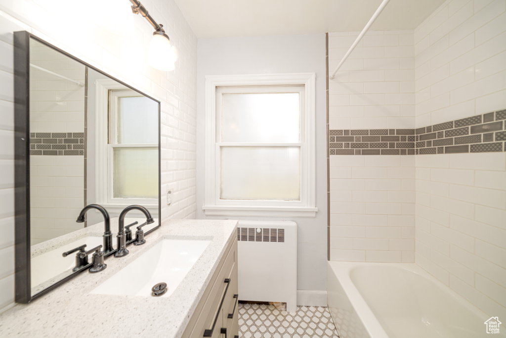 Bathroom featuring tiled shower / bath combo, tile floors, vanity, and radiator