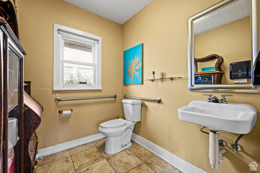 Bathroom with tile floors, toilet, and a textured ceiling
