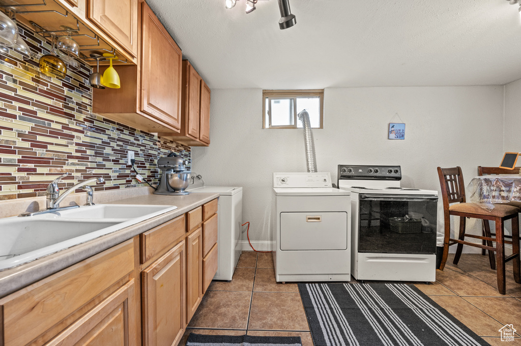 Laundry area with washing machine and clothes dryer, rail lighting, sink, and light tile floors