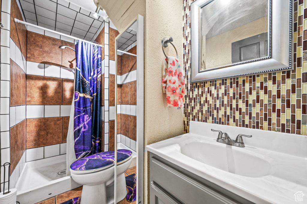 Bathroom featuring toilet, large vanity, tile walls, and a shower with curtain